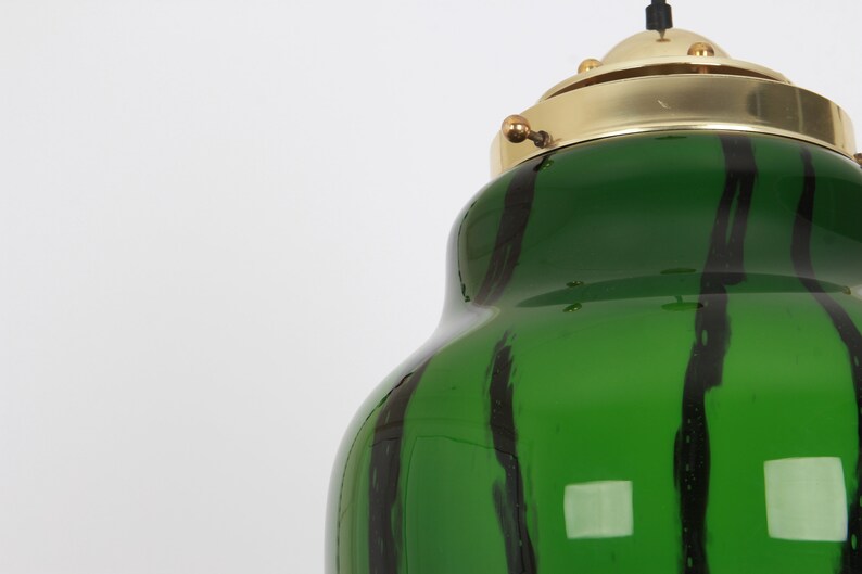May include: A green glass pendant light with black stripes and a brass top.