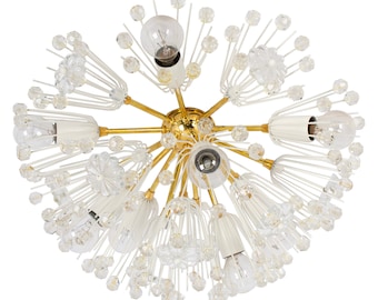 May include: A gold-toned chandelier with white and clear glass accents. The chandelier has a starburst design with multiple arms extending outward. Each arm has a clear glass bulb and a white glass shade.