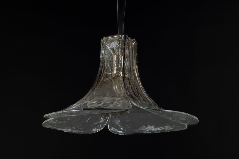 May include: A clear glass pendant light fixture with a bell-shaped top and a three-petal flower-shaped bottom.