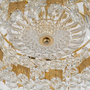 Peut inclure: Un lustre dor&eacute; avec des cristaux de verre transparents et un bol central en verre facett&eacute;. Le lustre a une forme circulaire avec plusieurs niveaux de cristaux.
