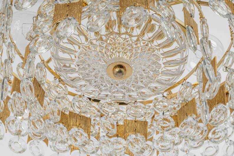 Peut inclure: Un lustre dor&eacute; avec des cristaux de verre transparents et un bol central en verre facett&eacute;. Le lustre a une forme circulaire avec plusieurs niveaux de cristaux.