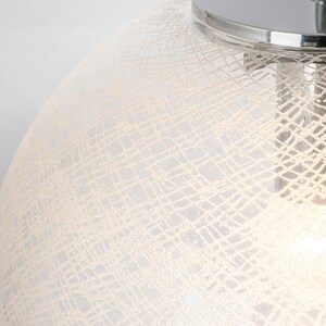 Peut inclure: Un luminaire suspendu en verre blanc avec un dessus chrom&eacute; et un motif d&eacute;licat tiss&eacute;.