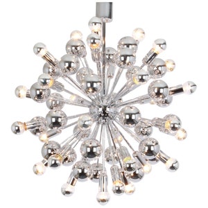 Op de afbeelding: Een chromen Sputnik-kroonluchter met meerdere ronde lampen. De kroonluchter heeft een stervormig ontwerp met veel armen die naar buiten uitstrekken.