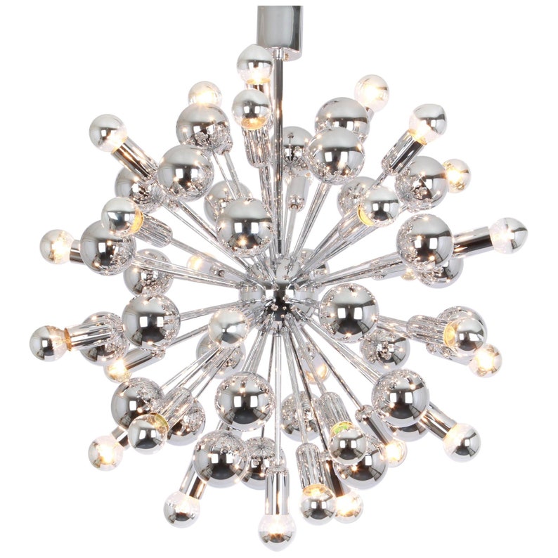 Op de afbeelding: Een chromen Sputnik-kroonluchter met meerdere ronde lampen. De kroonluchter heeft een stervormig ontwerp met veel armen die naar buiten uitstrekken.