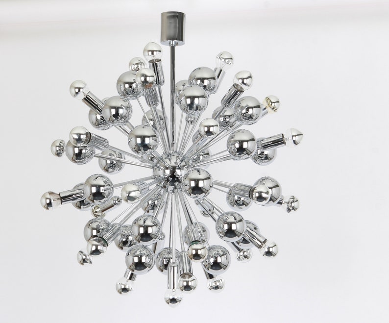 Op de afbeelding: Een chromen Sputnik-kroonluchter met meerdere ronde lampen die naar buiten uitstrekken vanaf een centraal punt.
