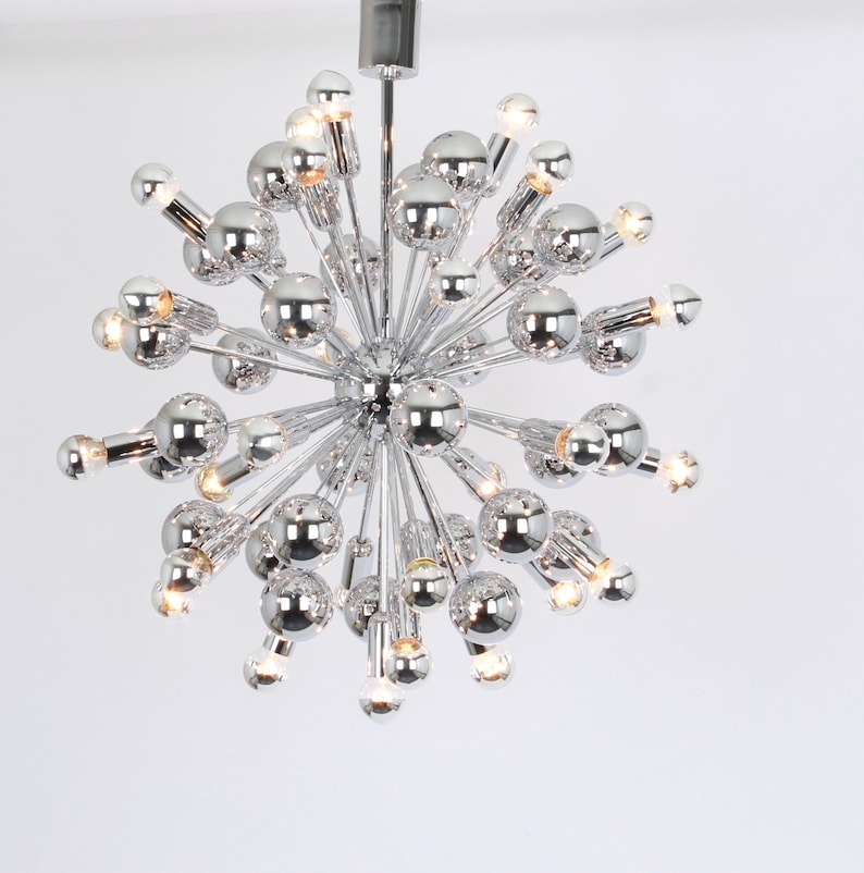 Op de afbeelding: Een chromen Sputnik-kroonluchter met meerdere lampen. De kroonluchter heeft een ronde vorm met veel armen die naar buiten uitstrekken.