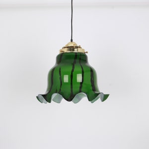 May include: A green glass pendant light with black stripes and a ruffled edge. The light fixture has a brass top and a black cord.
