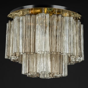 May include: A multi-tiered ceiling light fixture with a black metal base and clear glass tubes. The tubes are arranged in a cascading pattern, creating a modern and elegant look.