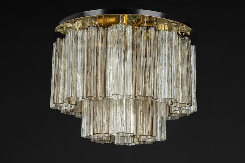 May include: A multi-tiered ceiling light fixture with a black metal base and clear glass tubes. The tubes are arranged in a cascading pattern, creating a modern and elegant look.