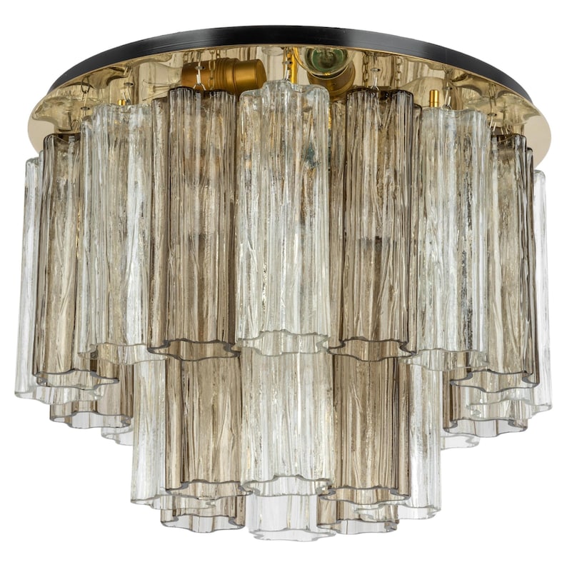 May include: A gold and black ceiling light fixture with multiple tiers of clear and amber glass tubes.