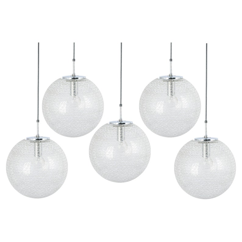 Peut inclure: Ensemble de cinq lampes suspendues en verre globe transparent avec des luminaires en chrome. Chaque globe a une surface textur&eacute;e et est suspendu &agrave; un cordon fin.