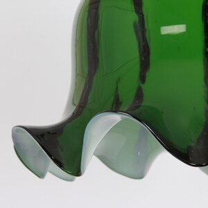 May include: A green glass lampshade with black stripes and a ruffled edge.