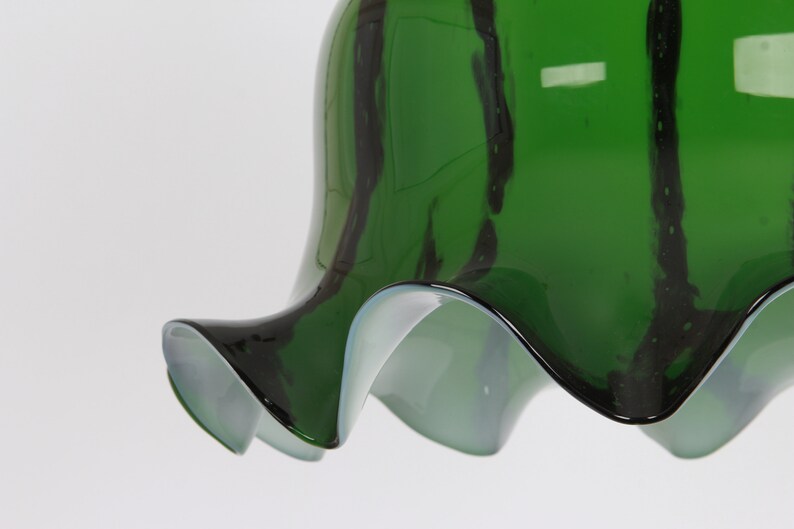 May include: A green glass lampshade with black stripes and a ruffled edge.
