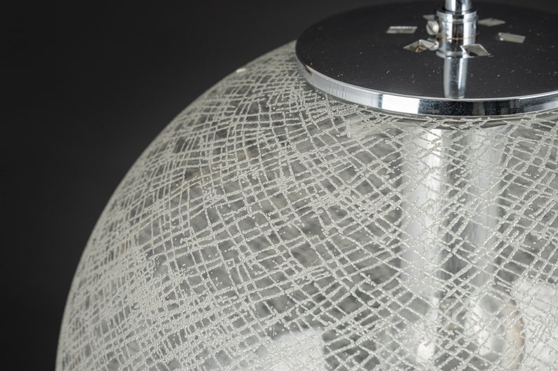 Peut inclure: Gros plan d'un luminaire suspendu en chrome et en verre. L'abat-jour en verre est textur&eacute; avec un motif en croisillons.