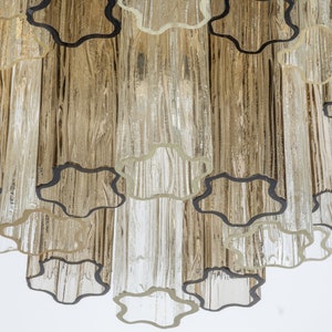 May include: A close-up of a chandelier with clear glass tubes and black metal accents. The tubes are arranged in a cascading pattern, creating a unique and modern design.