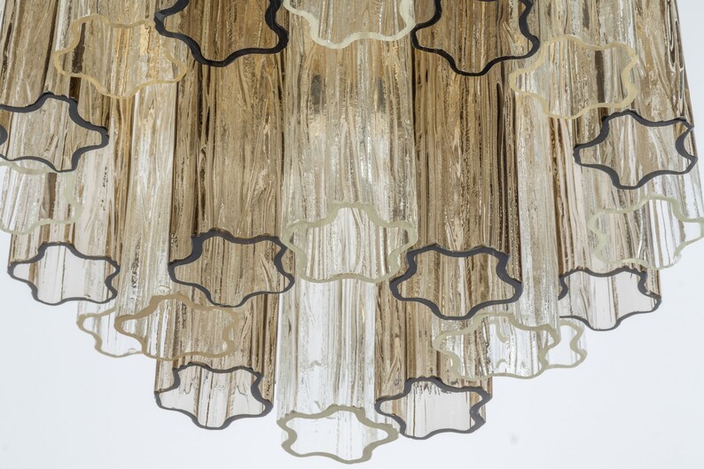 May include: A close-up of a chandelier with clear glass tubes and black metal accents. The tubes are arranged in a cascading pattern, creating a unique and modern design.