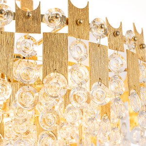 Peut inclure: Un lustre dor&eacute; avec des cristaux de verre transparents suspendus &agrave; un cadre g&eacute;om&eacute;trique. Le lustre a un design moderne et serait une pi&egrave;ce ma&icirc;tresse dans n'importe quelle pi&egrave;ce.