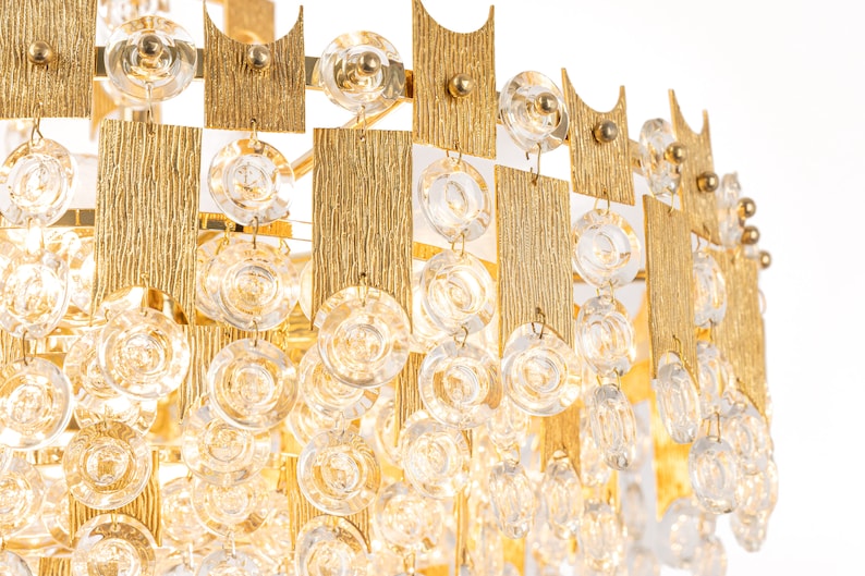 Peut inclure: Un lustre dor&eacute; avec des cristaux de verre transparents suspendus &agrave; un cadre g&eacute;om&eacute;trique. Le lustre a un design moderne et serait une pi&egrave;ce ma&icirc;tresse dans n'importe quelle pi&egrave;ce.