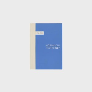 Può includere: Un'agenda blu con il dorso color crema e una piccola etichetta color crema con la scritta day-free. La copertina presenta il testo bianco HOBONICHI TECHO 2027. L'agenda ha una forma rettangolare e un design pulito e a tinta unita.