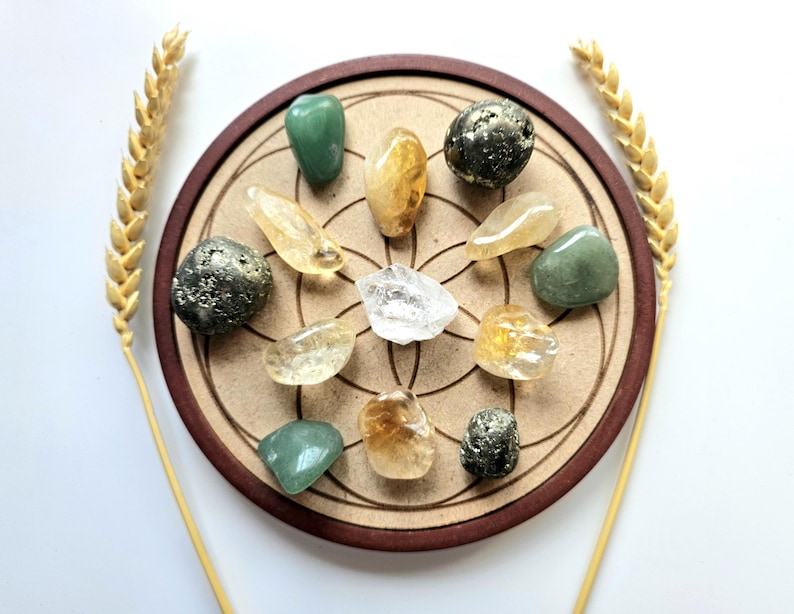 Pu&ograve; includere: Una collezione di pietre preziose lucide di vari colori, tra cui verde, giallo e trasparente, disposte su una base circolare in legno con un bordo marrone. Due spighe di grano fiancheggiano la composizione. Le pietre preziose sono di forme e dimensioni diverse.