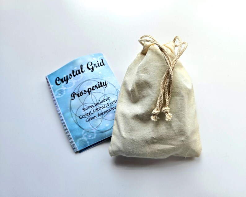 Pu&ograve; includere: Un libretto azzurro con le parole "Crystal Grid Prosperity" accanto a un sacchetto beige con coulisse. Il libretto elenca le pietre incluse: Cristallo, Citrino, Pirite e Avventurina verde. La borsa &egrave; in tessuto color naturale.