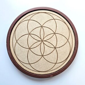 Pu&ograve; includere: Un sottobicchiere rotondo in legno con un bordo marrone scuro e un centro marrone chiaro. Il centro presenta un design tagliato al laser di cerchi sovrapposti, creando un motivo geometrico. Il sottobicchiere &egrave; progettato per l'uso con tazze e bicchieri.