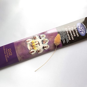 Peut inclure: Un paquet de 22 bâtonnets d'encens mystiques avec le texte "African 7 Potencias" en anglais et en espagnol. L'emballage violet et noir présente un motif ovale et des illustrations. Une fleur séchée est à côté.