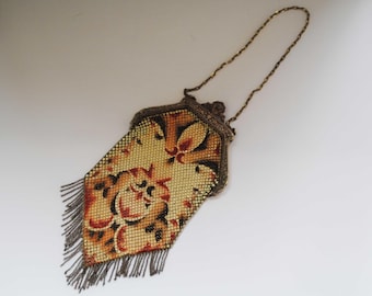 May include: Vintage metal mesh purse with a floral design in shades of yellow, red, and brown. The purse has a decorative frame, a chain handle, and a fringe at the bottom. A classic accessory.