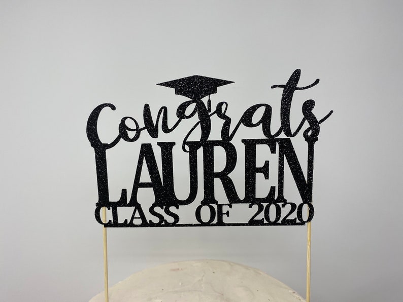 May include: Black glitter graduation cake topper with the text "Congrats Lauren Class of 2020".