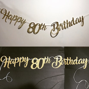 K&ouml;nnte beinhalten: Goldene Glitzergirlande mit dem Text "Happy 80th Birthday".