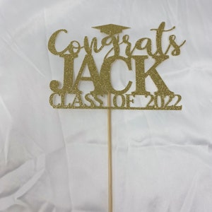 May include: Gold glitter graduation cake topper with the text "Congrats Jack Class of 2022".