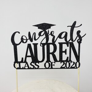 May include: Black glitter graduation cake topper with the text "Congrats Lauren Class of 2020".