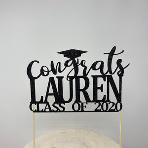 May include: Black glitter graduation cake topper with the text "Congrats Lauren Class of 2020".
