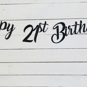 K&ouml;nnte beinhalten: Happy 21st Birthday Banner in schwarzen Schriftzeichen auf wei&szlig;em Holz Hintergrund.