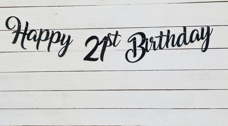 K&ouml;nnte beinhalten: Happy 21st Birthday Banner in schwarzen Schriftzeichen auf wei&szlig;em Holz Hintergrund.