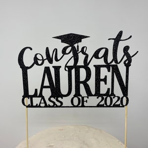May include: Black glitter graduation cake topper with the text "Congrats Lauren Class of 2020".