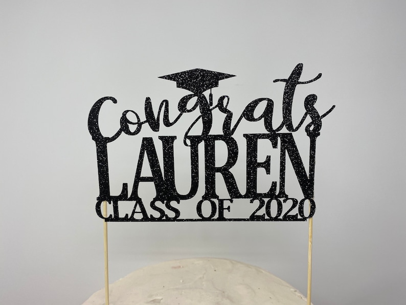 May include: Black glitter graduation cake topper with the text "Congrats Lauren Class of 2020".