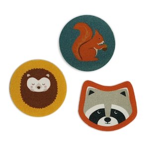 Può includere: Tre toppe rotonde in tessuto con disegni di animali del bosco. Uno scoiattolo che tiene una ghianda su uno sfondo blu-verde, un riccio su uno sfondo giallo e un procione su uno sfondo arancione.