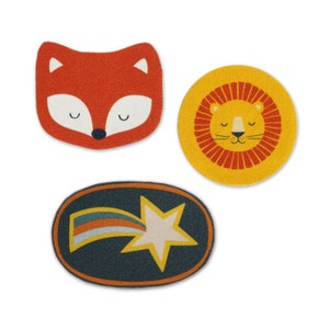 May include: Three felt patches with different designs. The first patch is orange and features a fox face. The second patch is yellow and features a lion face. The third patch is dark blue and features a white star with a rainbow tail.