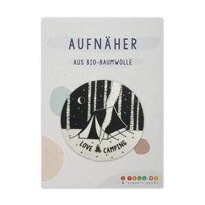 Può includere: Un toppa termoadesiva in bianco e nero con una tenda da campeggio in una scena di foresta. La toppa dice "Love Camping" e "Aufnäher aus Bio-Baumwolle".