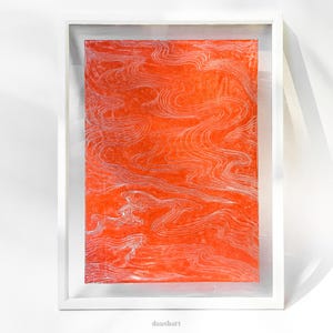 May include: A rectangular artwork featuring a vibrant orange background with intricate, flowing white line patterns that resemble water currents or topographical contours, encased within a simple, clean white floating frame.