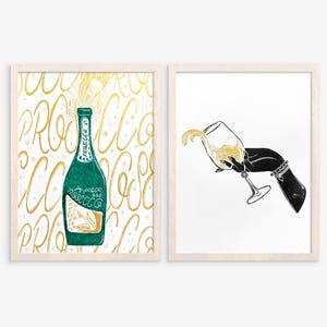 Set di 2 stampe linoleografiche a parete con scritta "Prosecco verde oro" e mano di donna nera con bicchiere di vino bianco, decorazione per la cucina, arte invernale e festiva.