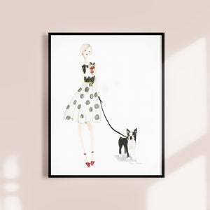 Op de afbeelding: Een aquarel-illustratie van een vrouw in een zwart-witte polkadotjurk die een zwart-witte Boston Terrier uitlaat. De vrouw draagt rode schoenen en een zwart-wit geprint topje.