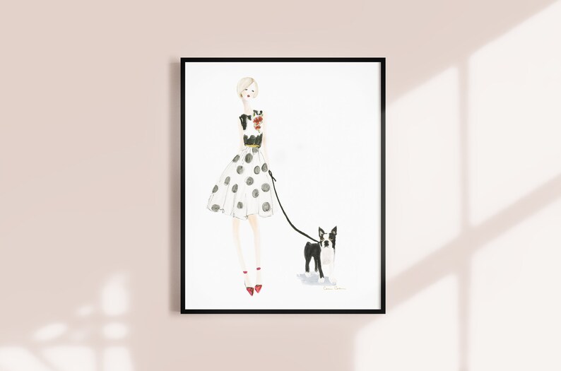 Op de afbeelding: Een aquarel-illustratie van een vrouw in een zwart-witte polkadotjurk die een zwart-witte Boston Terrier uitlaat. De vrouw draagt rode schoenen en een zwart-wit geprint topje.