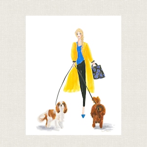 Op de afbeelding: Een vrouw in een gele jas loopt met twee honden aan de lijn. De honden zijn bruin en wit, en de vrouw draagt een blauwe en zwarte bloemenhandtas.