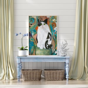 May include: A framed painting of a black and white cat sitting on a green rock. The cat is surrounded by colorful abstract shapes and lines. The painting is hanging on a white wall above a light blue console table with two wicker baskets.