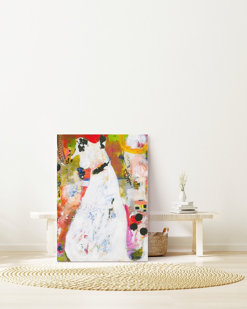 Op de afbeelding: Abstracte schilderij van een witte figuur met zwarte accenten op een kleurrijke achtergrond. Het schilderij is ingelijst en hangt aan een witte muur.