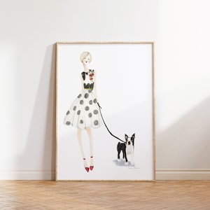 Op de afbeelding: Een aquarelillustratie van een vrouw in een witte polkadotrok en een zwart topje die een Boston Terrier aan de lijn uitlaat. De vrouw draagt rode schoenen en heeft blond haar. De achtergrond is wit.