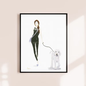 May include: Watercolour print of a woman walking a white dog. The woman wears a black outfit and carries a blue bag. The dog is on a lead. The artwork is framed in a black frame.