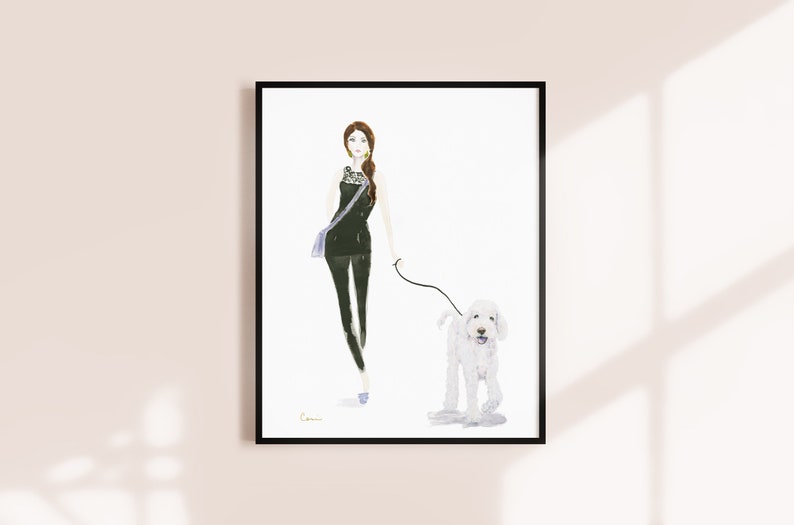 May include: Watercolour print of a woman walking a white dog. The woman wears a black outfit and carries a blue bag. The dog is on a lead. The artwork is framed in a black frame.